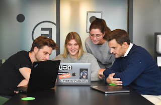 Four people looking at a laptop screen discussing the importance of resource forecasting.